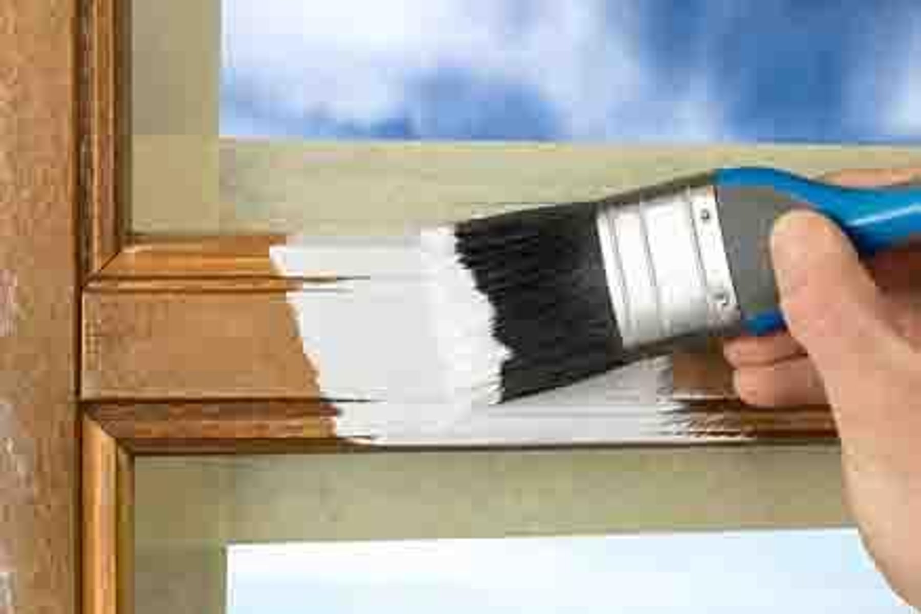 Handwerker streicht Fensterrahmen mit Pinsel